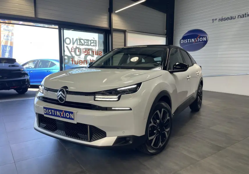 Citroën C4 blanche vue 3/4 avant droit en intérieur avec toit noir et jantes alliage noires.