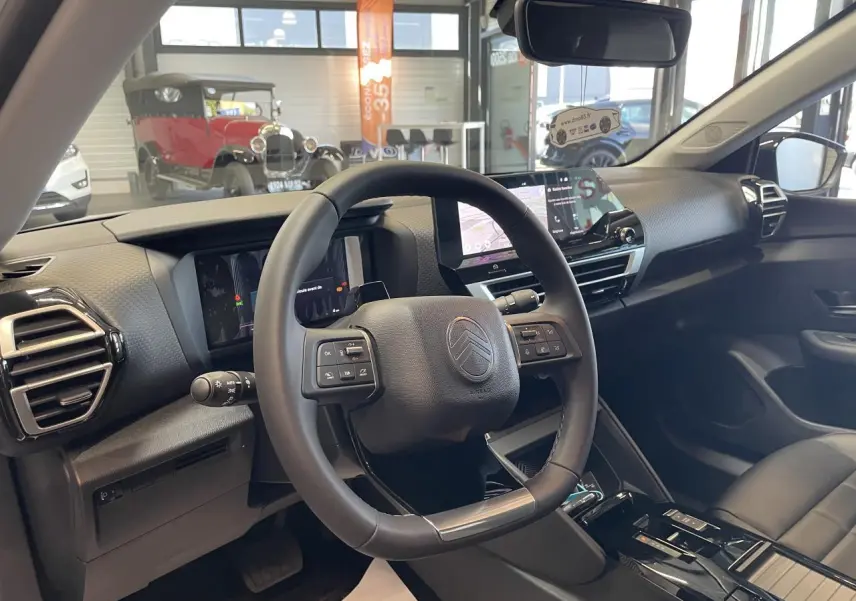 Intérieur de la Citroën C4 blanc, vue du poste de conduite avec volant cuir et écran tactile central.