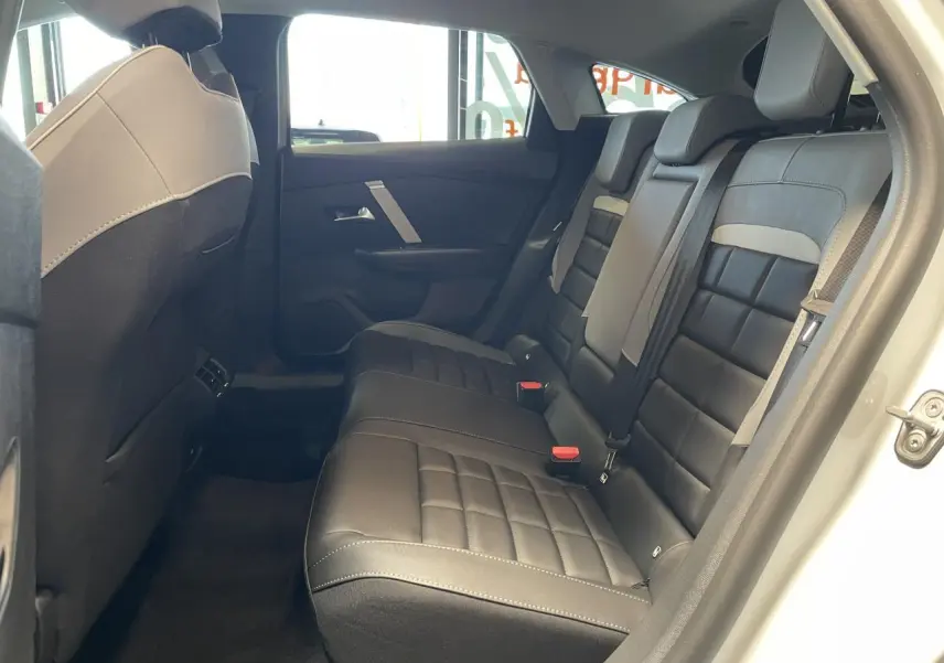 Vue côté droit de la banquette arrière noire et grise de la Citroën C4 blanche, avec portes ouvertes et habillage intérieur sombre.