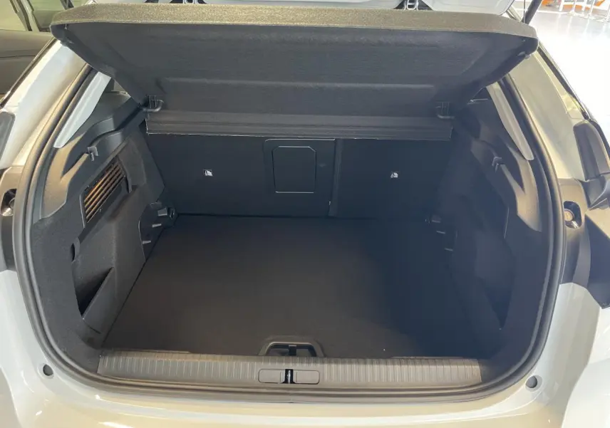 Coffre ouvert vu de l'arrière d'une Citroën C4 blanche, montrant un espace de chargement propre et spacieux.
