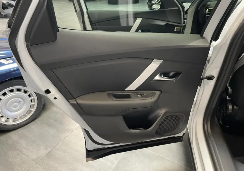 Vue intérieure sur la porte arrière gauche ouverte d'une Citroën C4 blanche, avec garniture noire et poignée argentée.
