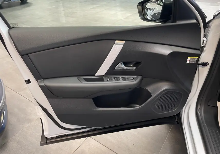 Vue intérieure de la porte avant gauche blanche d’une Citroën C4 2026 avec garniture noire et commande de vitres.
