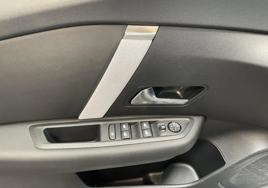 Détail de la porte avant gauche noire de la Citroën C4 avec commandes électriques et poignée argentée.