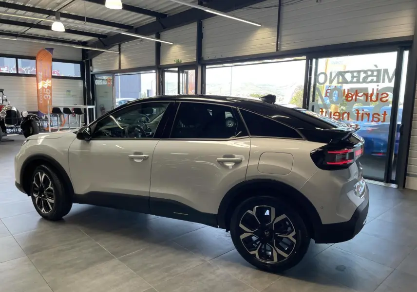 Citroën C4 blanche vue de profil côté gauche, toit noir bi-ton et jantes alliage 18 pouces en showroom.