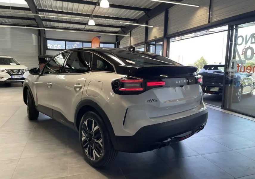 Vue 3/4 arrière droite d'une Citroën C4 blanche avec toit noir et jantes alliage 18 pouces dans un showroom.