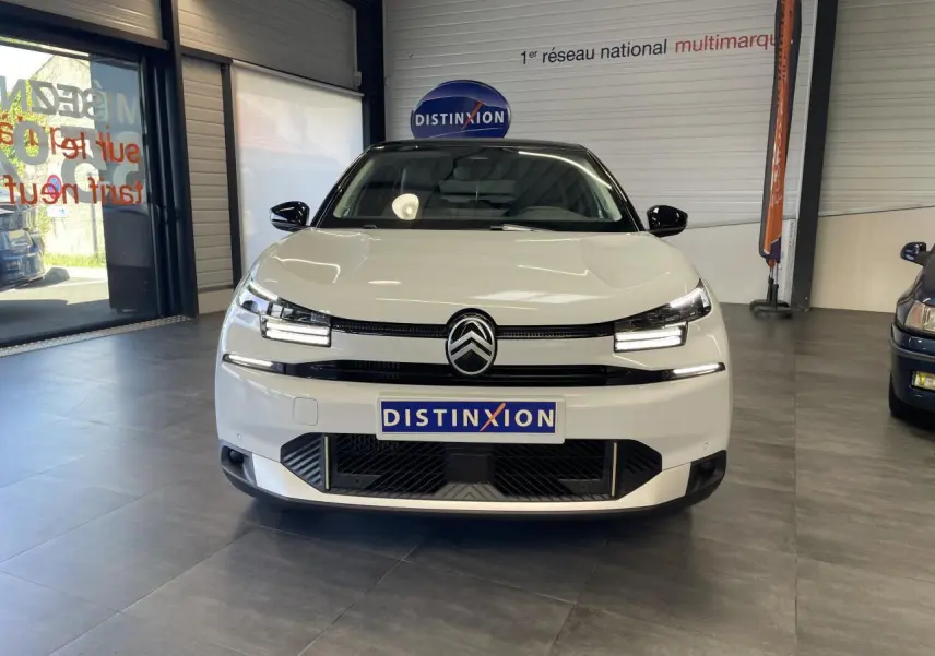 Citroën C4 blanche vue de face en intérieur, avec toit bi-ton noir et signature lumineuse LED distinctive.
