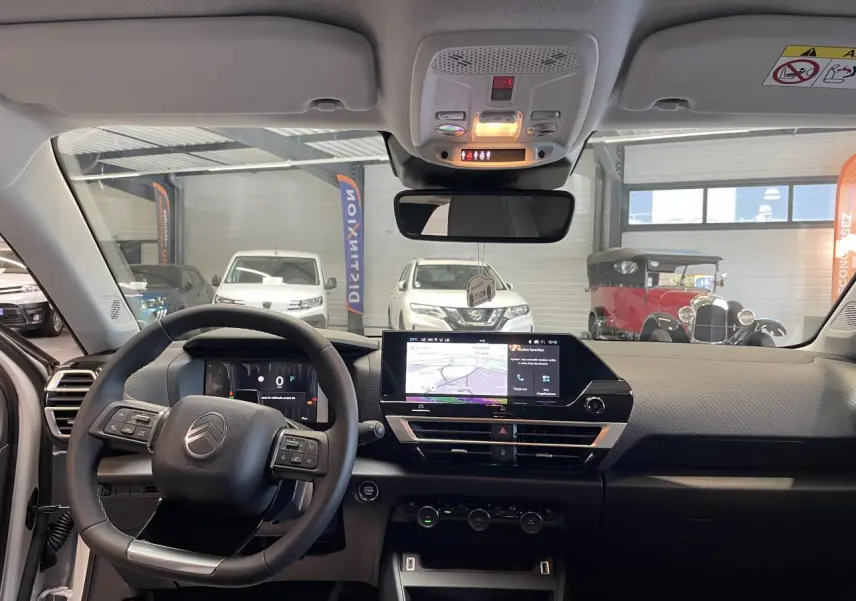 Intérieur Citroën C4 2026 vu de face, tableau de bord noir avec écran tactile central et volant multifonctions.