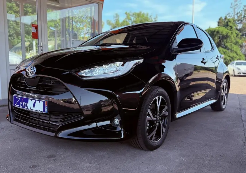 Toyota Yaris Hybrid noire vue en 3/4 avant droit, avec jantes alliage et calandre imposante brillante.