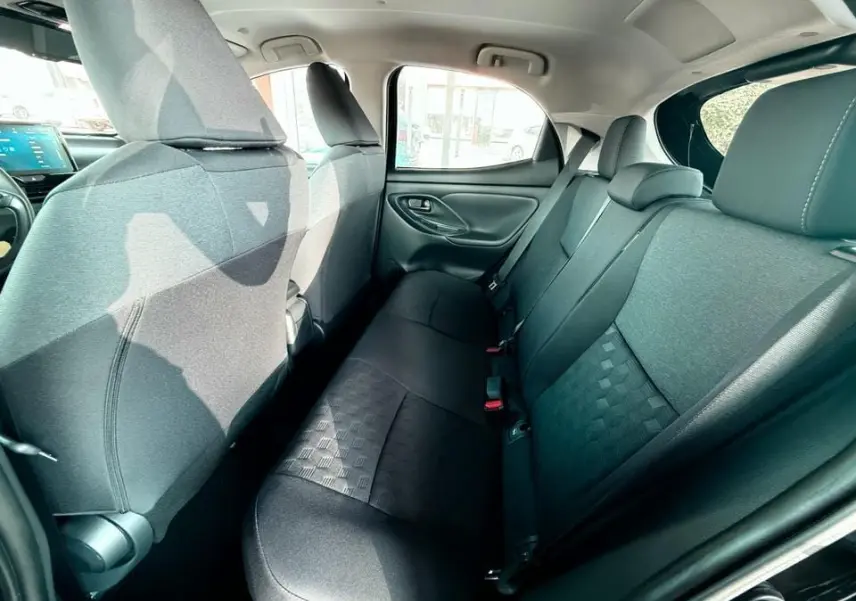 Vue intérieure arrière côté droit montrant les sièges noirs en tissu de la Toyota Yaris Hybrid 2025.
