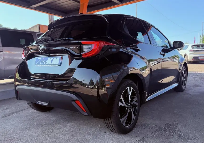 Toyota Yaris Hybrid noire vue en 3/4 arrière droit, avec feux arrière LED et jantes alliage noires.
