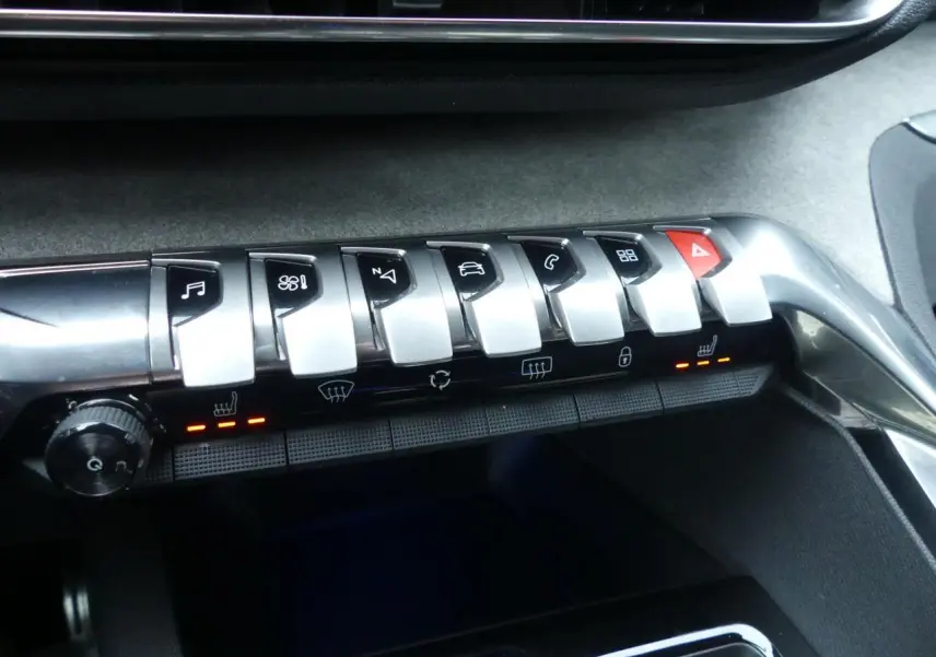 Gros plan sur la rangée de commandes chromées et boutons tactiles du tableau de bord du Peugeot 5008 GT noir métallisé.
