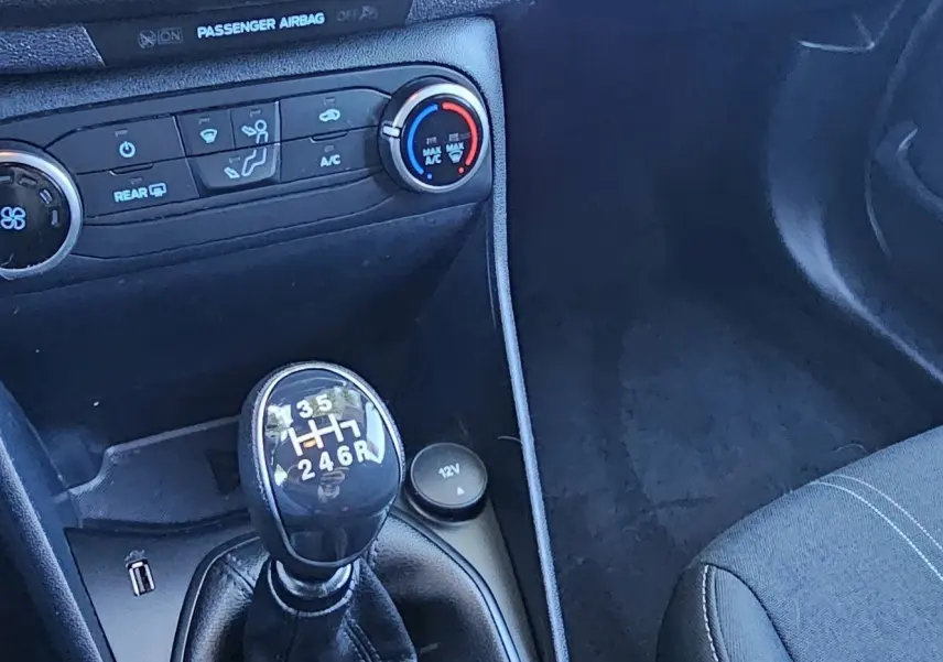 Gros plan sur la console centrale de la Ford Fiesta 2021 montrant le levier de vitesse manuel et les commandes de climatisation.