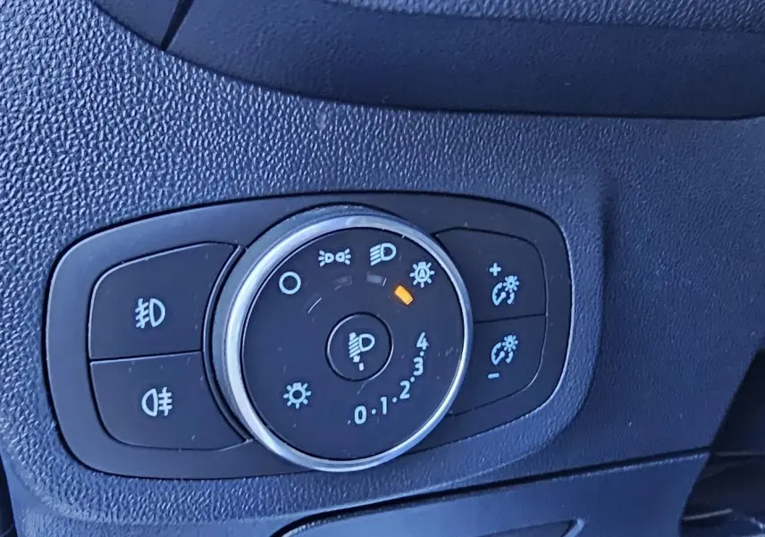 Gros plan sur le bouton de réglage des phares d'une Ford Fiesta 1.1 Ecoboost gris lunaire métal de 2021.