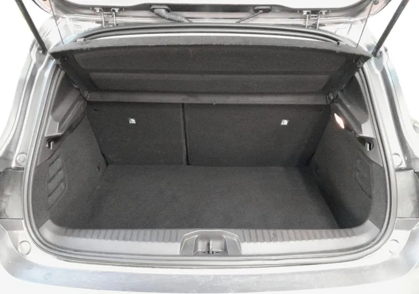 Coffre ouvert d'une Renault Clio V gris schiste, vue arrière montrant l'espace de chargement vide et la trappe de roue de secours.