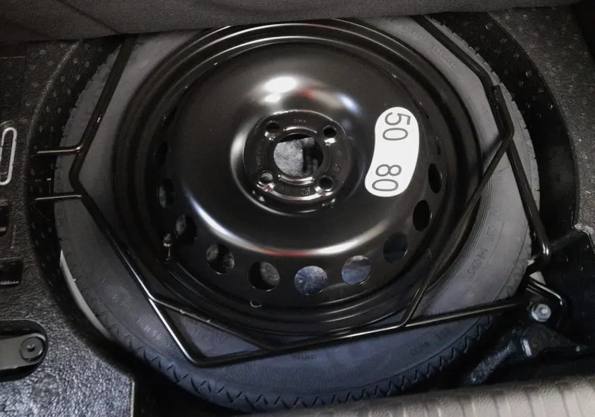 Gros plan sur la roue de secours temporaire noire dans le coffre de la Renault Clio V gris schiste 2025.