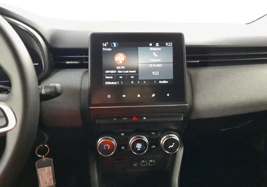 Vue intérieure centrée sur la console centrale de la Renault Clio V E-Tech avec écran tactile et commandes climatisation.
