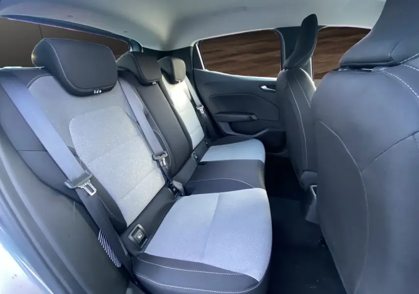 Vue intérieure arrière droite de la Renault Clio V E-Tech gris schiste, montrant les sièges arrière en tissu gris et noir avec ceintures de sécurité.