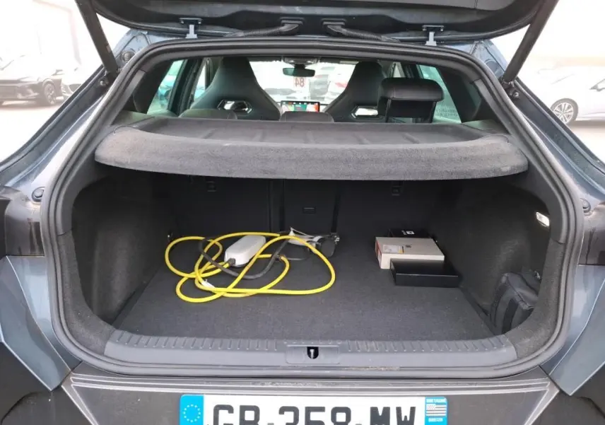 Vue arrière du coffre ouvert d'une CUPRA Formentor gris, avec câble de recharge jaune visible à l'intérieur.