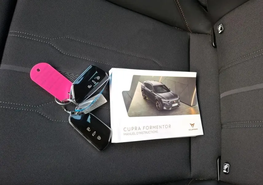 Manuel d'instructions avec photo du CUPRA Formentor gris en 3/4 avant et deux clés sur siège textile noir.
