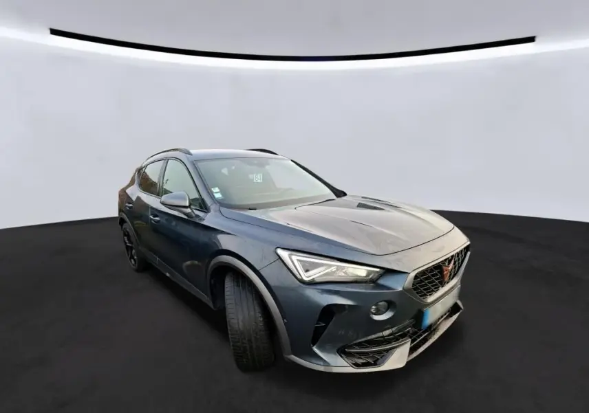 Vue 3/4 avant droit du CUPRA Formentor gris avec calandre marquée et phares LED allumés dans un studio.