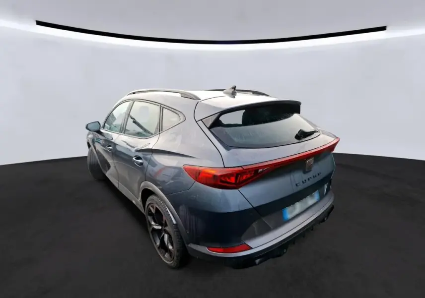 Vue 3/4 arrière droite d'un CUPRA Formentor gris avec feux arrière en bandeau lumineux et jantes noires 19 pouces.