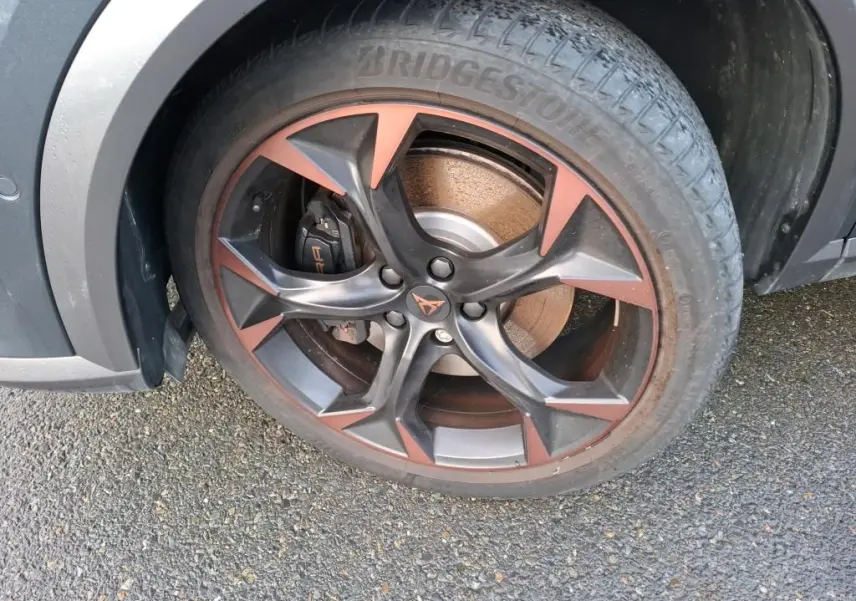 Gros plan sur la jante alliage 19 pouces bicolore noir et copper du côté avant droit du CUPRA Formentor gris.