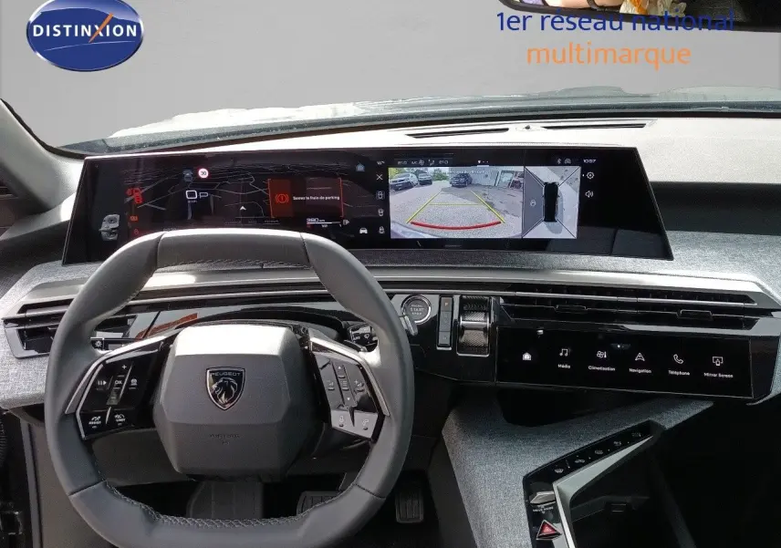 Vue intérieure frontale du tableau de bord et volant gris noir du Peugeot 5008 2025 avec écran numérique large et caméra de recul affichée.