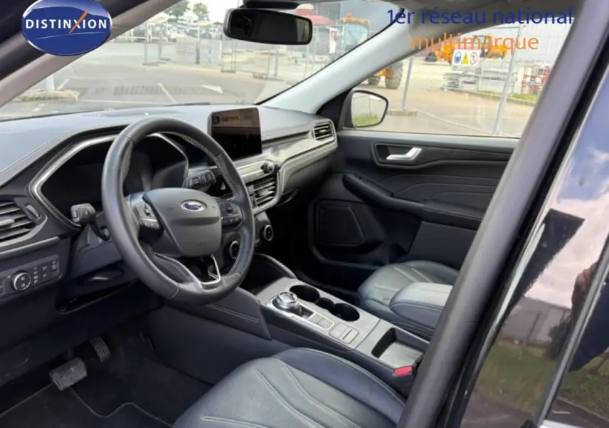 Intérieur avant droit du Ford Kuga noir 2024, avec tableau de bord moderne, écran tactile et sièges sport en cuir.