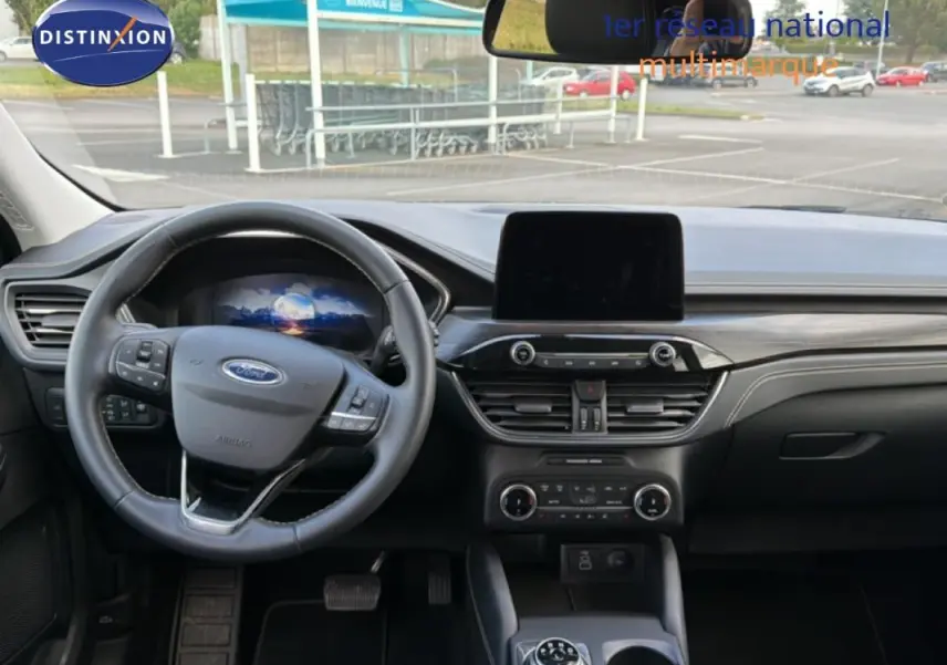 Vue intérieure avant du Ford Kuga 2024 noir, montrant le volant multifonction, écran tactile central et tableau de bord moderne.