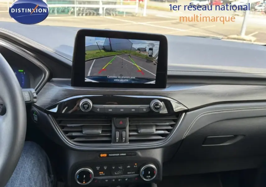 Vue intérieure du tableau de bord du Ford Kuga 2024 noir, avec écran tactile affichant la caméra de recul.
