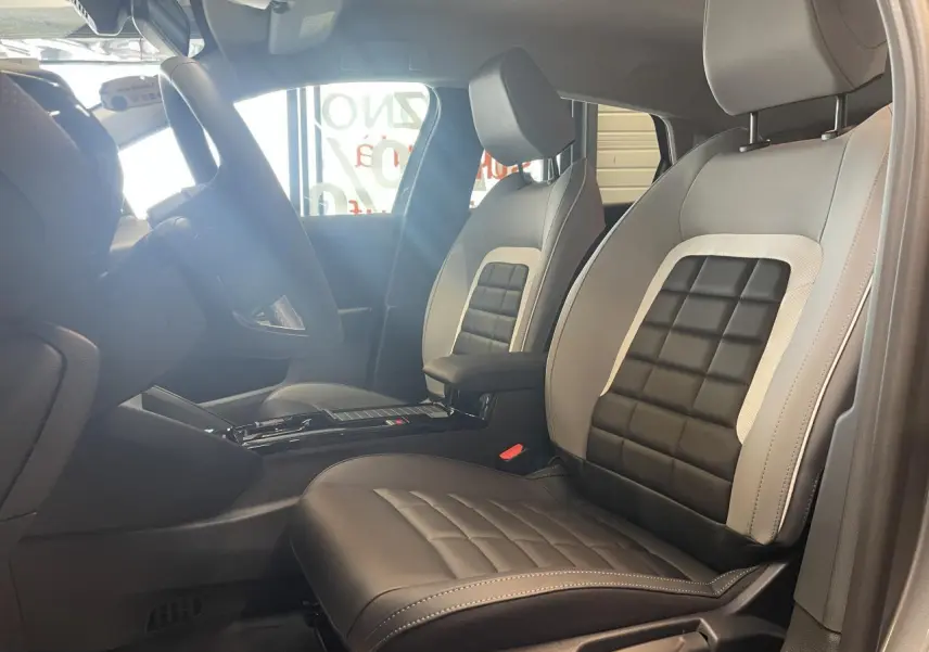 Vue intérieure côté conducteur de la Citroën C4 2026 avec sièges bi-ton gris clair et noir au design matelassé.