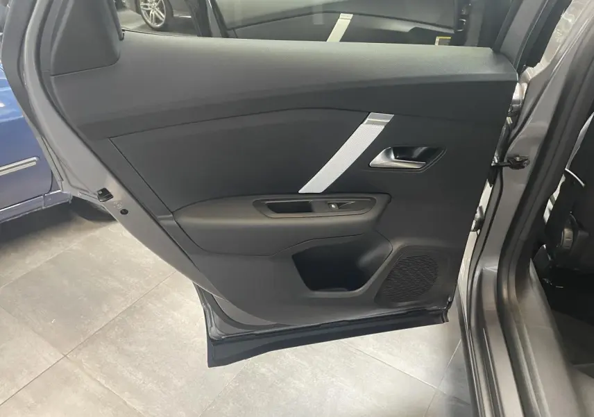 Porte arrière gauche ouverte d'une Citroën C4 grise, montrant le panneau intérieur noir avec insert argenté.