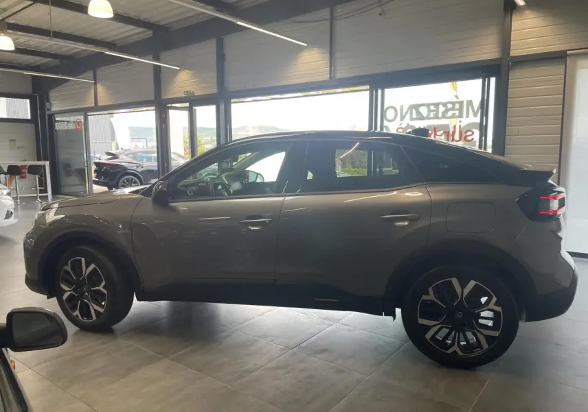 Vue de profil côté gauche d'une Citroën C4 gris métallisé avec jantes alliage 18'' et toit bi-ton noir en showroom.
