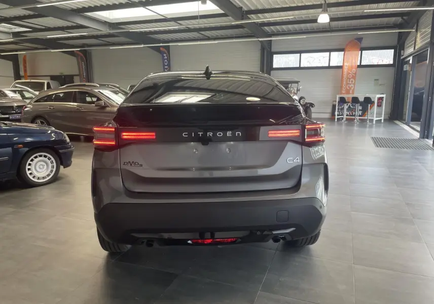 Vue arrière d'une Citroën C4 gris métallisé avec feux LED allumés dans un showroom lumineux.