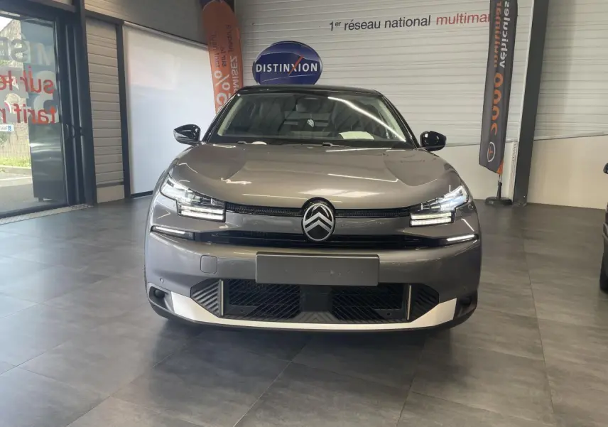 Vue avant d'une Citroën C4 gris métallisé avec toit noir dans un showroom, mettant en valeur ses phares LED distinctifs.