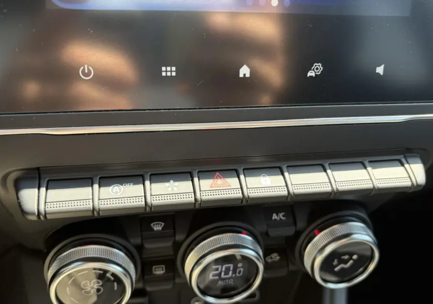 Gros plan sur la console centrale du Renault Captur 2024, montrant les commandes de climatisation et les boutons de fonction.
