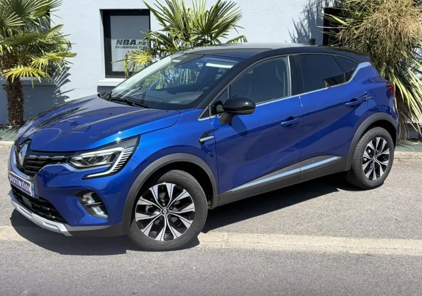 Renault Captur TCE 90 Techno 2024 en bleu Iron avec toit noir, vue 3/4 avant côté droit.