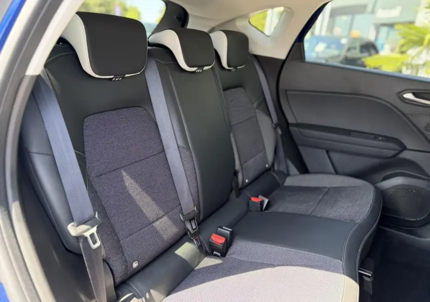 Vue intérieure des sièges arrière noirs et gris du Renault Captur TCE 90 Techno 2024, avec appuis-tête et ceintures visibles.