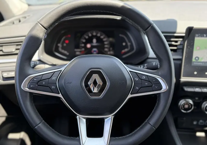 Vue rapprochée du volant noir de la Renault Captur 2024 avec commandes intégrées et tableau de bord numérique.