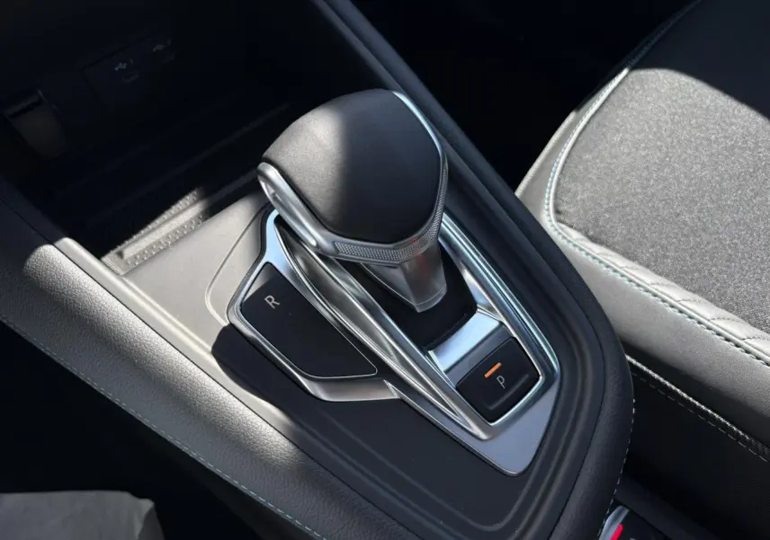 Le levier de vitesse automatique noir et chrome de la Renault SYMBIOZ 1.6 E-Tech, avec surpiqûres bleues sur la console.