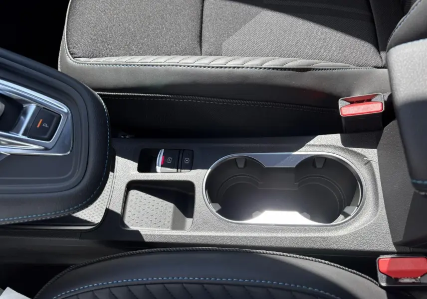 Gros plan sur la console centrale noire avec surpiqûres bleues et porte-gobelets du Renault SYMBIOZ Gris Rafale.