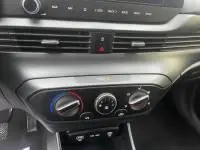 Gros plan sur la console centrale de la Hyundai i20 2025 noire, montrant les commandes de climatisation manuelle et la finition intérieure.
