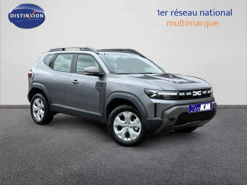Vue 3/4 avant d'un Dacia Duster 1.2 hybrid-G gris schiste avec jantes alu et barres de toit visibles.