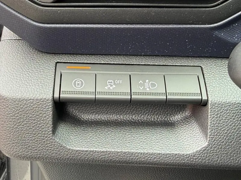 Gros plan sur les boutons de commande noirs du tableau de bord du Dacia Duster gris Schiste, version 1.2 hybrid-G 150ch Expression 4x4.