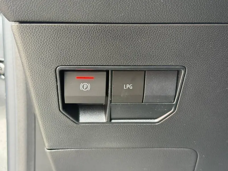 Gros plan sur les boutons de commande du frein à main électrique et du mode GPL dans un Dacia Duster gris Schiste 2026.