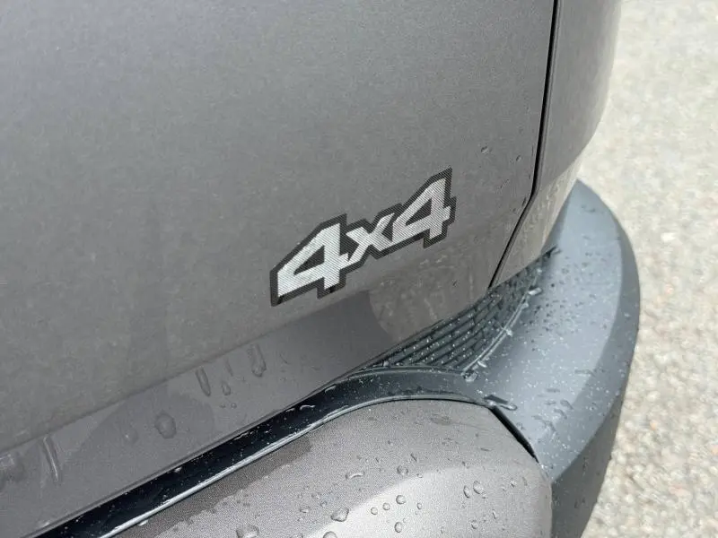 Gros plan sur l’inscription 4x4 en relief sur la carrosserie gris schiste du pare-chocs arrière du Dacia Duster.