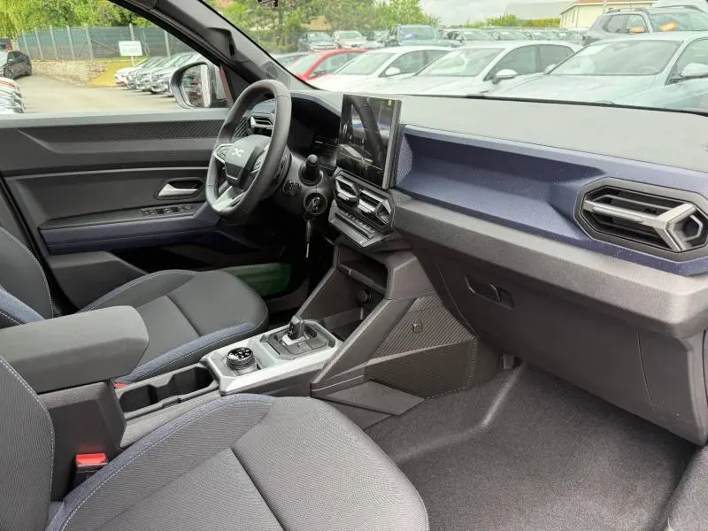 Vue intérieure côté conducteur du Dacia Duster 2026 gris Schiste, avec tableau de bord moderne et écran tactile vertical.
