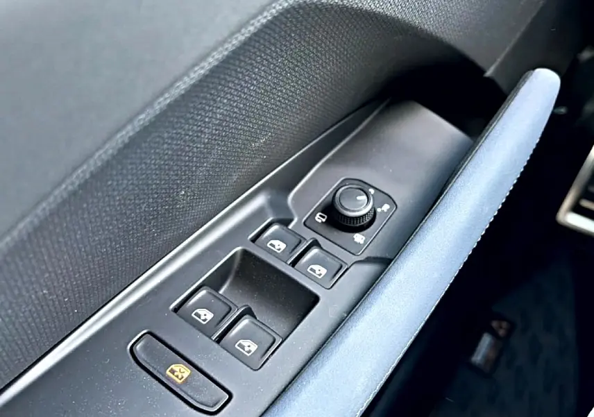 Gros plan sur les commandes de lève-vitres et rétroviseurs côté conducteur avec accoudoir bleu du CUPRA Terramar 2026.
