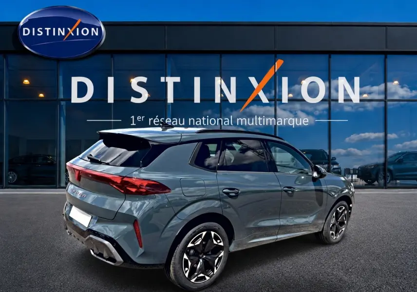 Vue 3/4 arrière droite d'un CUPRA Terramar bleu fjord avec jantes 19 pouces devant une vitrine Distinxion.