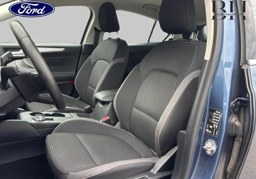 Vue intérieure côté conducteur d'une Ford Focus 2020 bleu azur métallisé, sièges tissu noir avec surpiqûres grises.